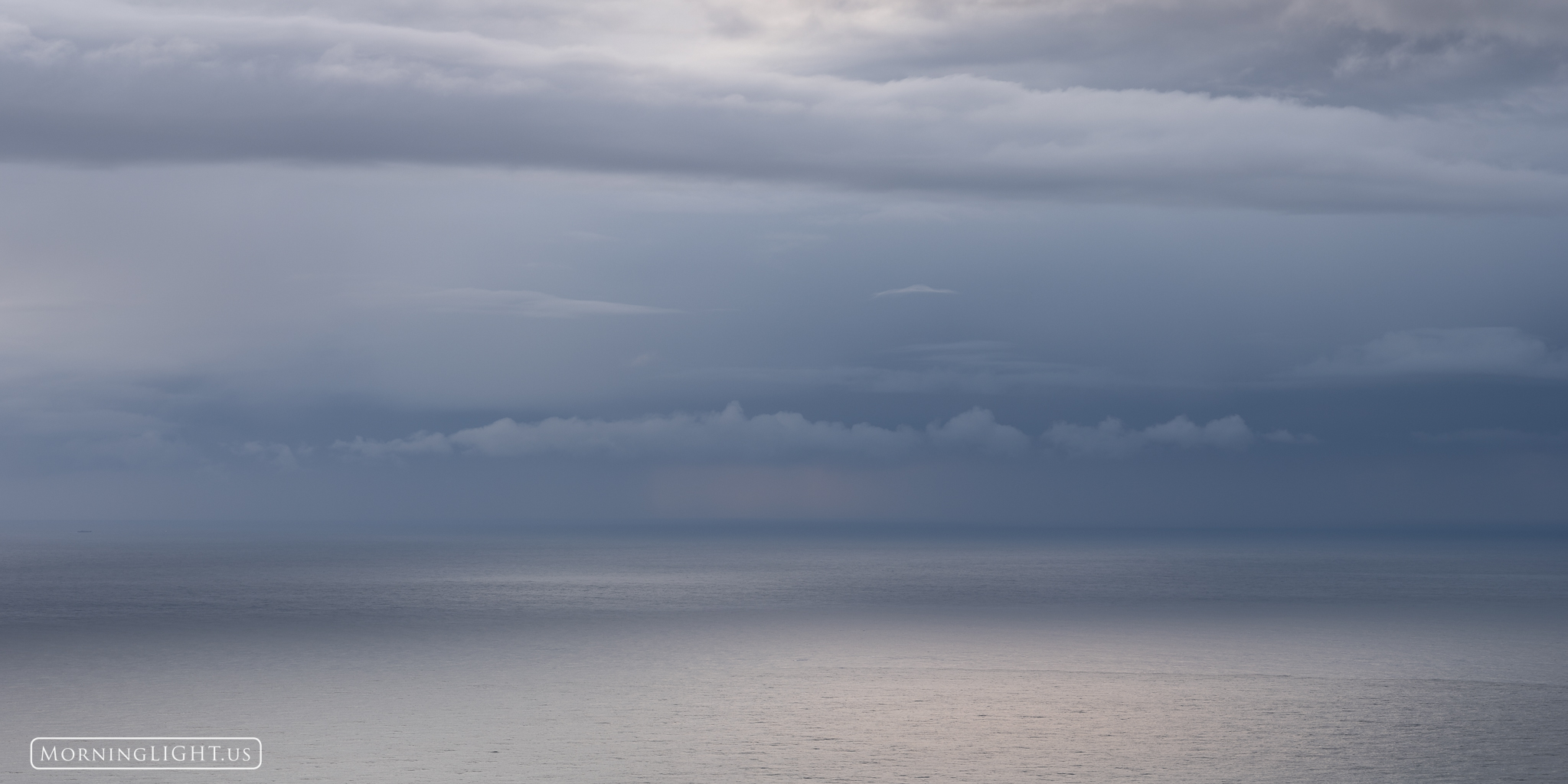 Above the tranquil sea, clouds floated in layers as the sunlight danced across the water.