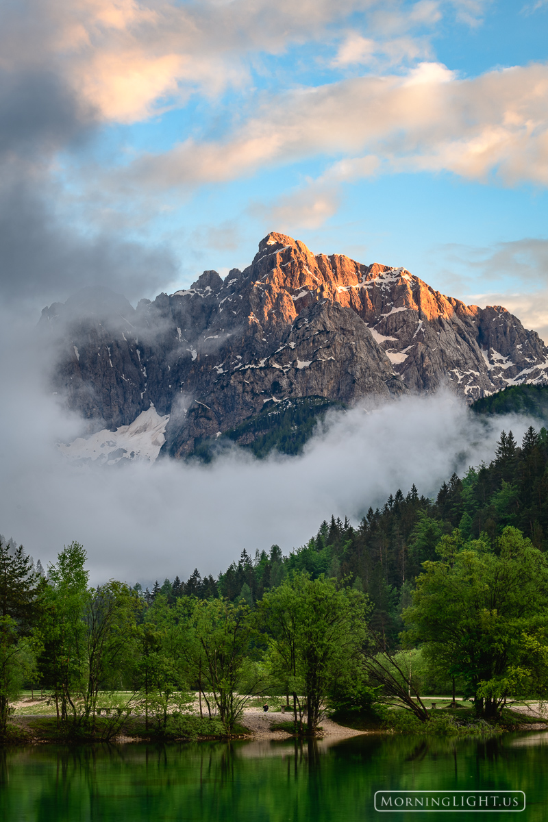 A breaking spring storm reveals Goličica mountain being lit by the setting sun.