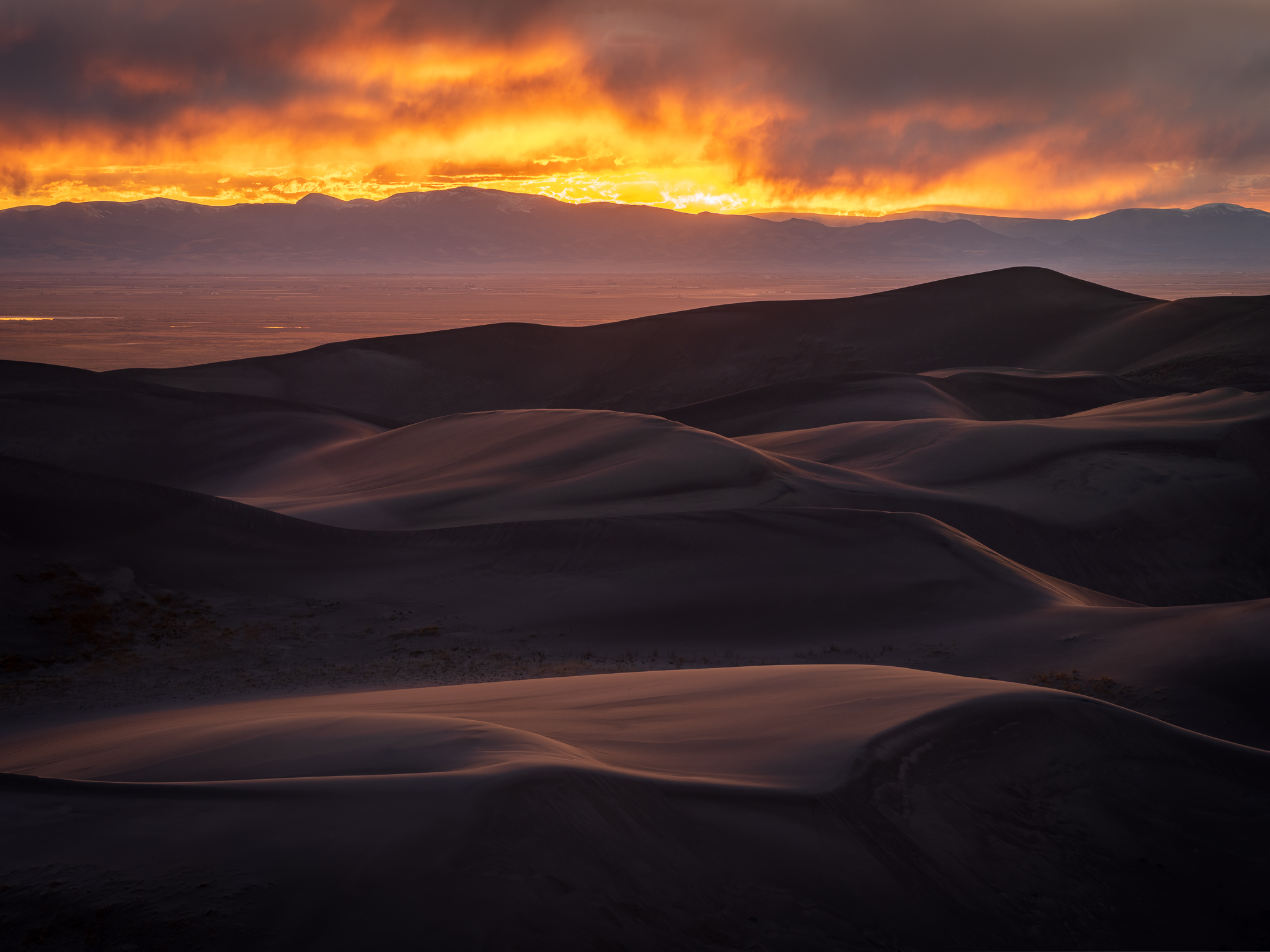As the sun went behind the distant mountains the clouds seemed to light on fire. Their burning light reflected on the dunes of...