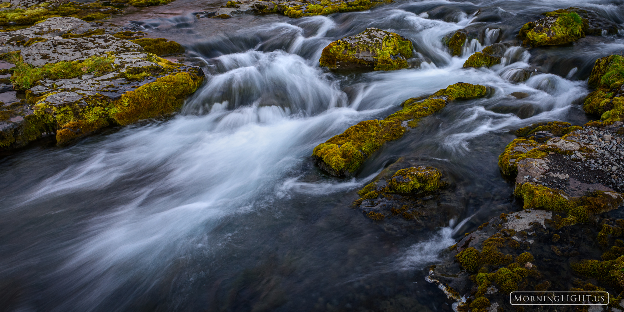 Lush moss covers the rocks beside a rushing stream in western Iceland.